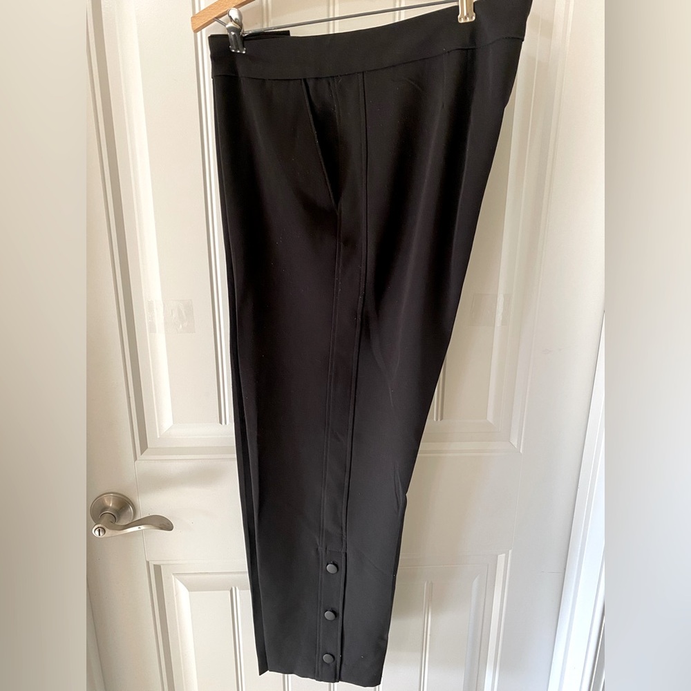 Black pants with side seam detailing and button detail at ankle.